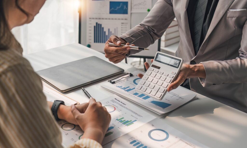 Two business people talk project strategy at office meeting room. Businessman discuss project planning with colleague at modern workplace while having conversation and advice on financial data report